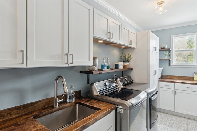 clothes washing area with cabinets, ornamental molding, sink, and washing machine and dryer