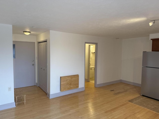 empty room with a textured ceiling and light wood-type flooring