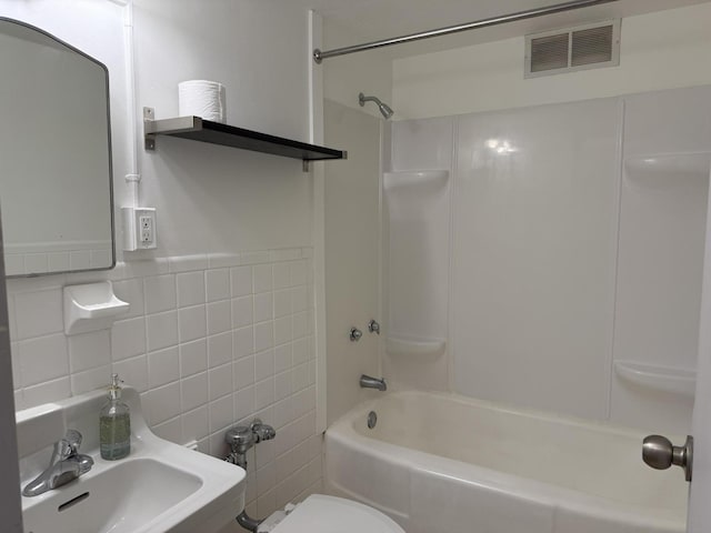 full bathroom featuring shower / bathing tub combination, sink, tile walls, and toilet