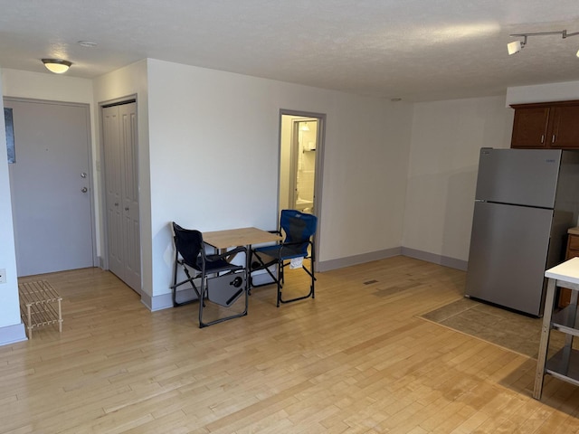 kitchen featuring a textured ceiling, stainless steel refrigerator, and light hardwood / wood-style floors