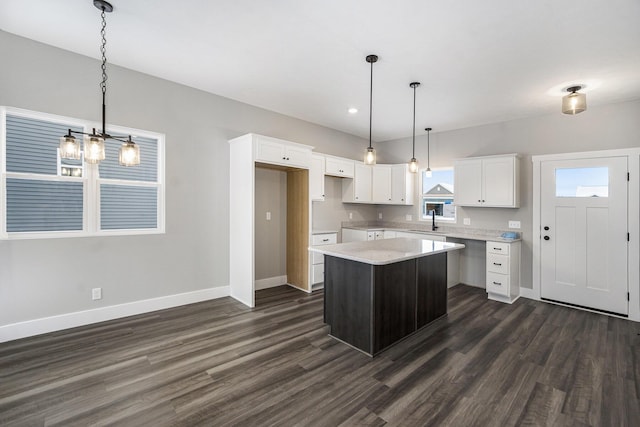 kitchen featuring sink, dark hardwood / wood-style floors, a center island, white cabinets, and decorative light fixtures