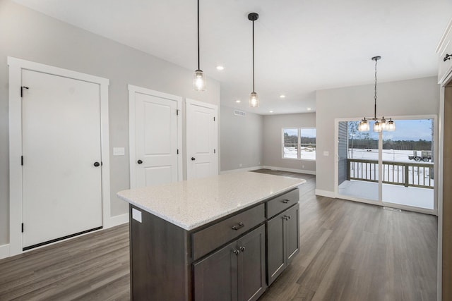 kitchen with dark hardwood / wood-style floors, dark brown cabinetry, decorative light fixtures, and light stone counters