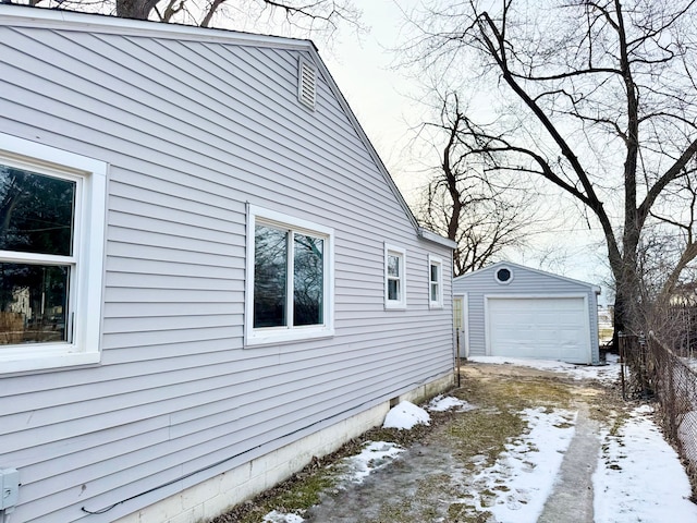 view of snow covered exterior featuring a garage and an outdoor structure