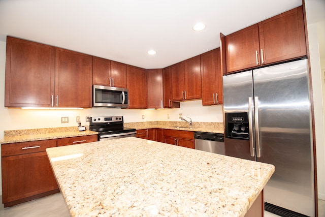 kitchen featuring light stone countertops, stainless steel appliances, and a sink