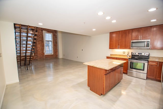 kitchen with concrete flooring, light stone counters, brick wall, a kitchen island, and appliances with stainless steel finishes