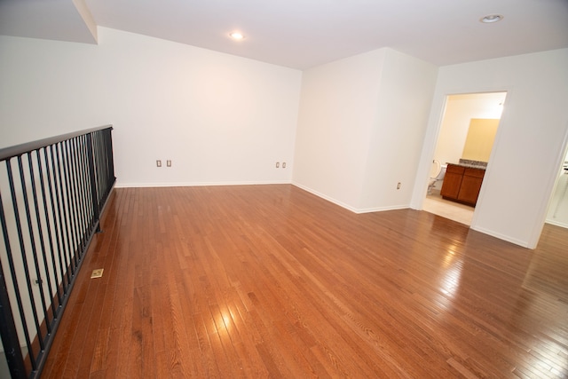 spare room featuring recessed lighting, hardwood / wood-style flooring, and baseboards