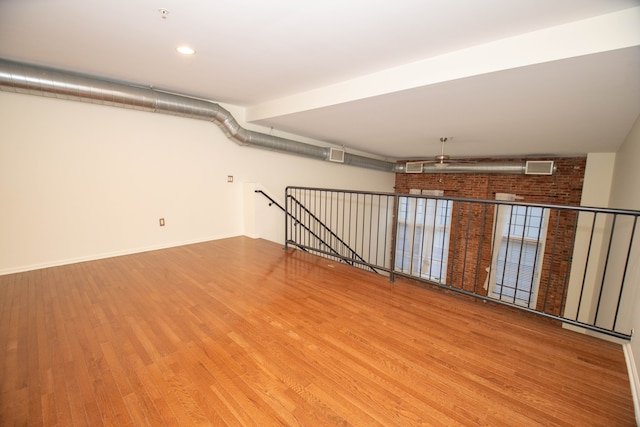 below grade area featuring brick wall, baseboards, and wood finished floors