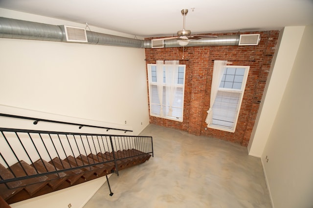 interior space with concrete flooring, visible vents, and brick wall