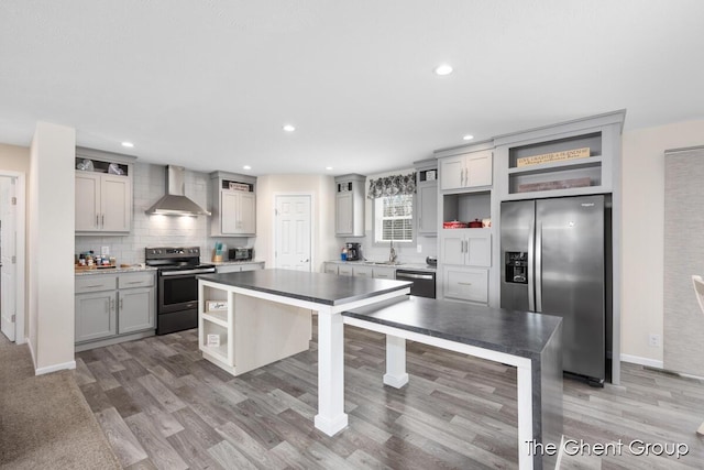 kitchen featuring appliances with stainless steel finishes, sink, gray cabinetry, a center island, and wall chimney exhaust hood