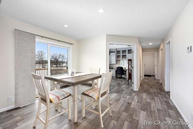 dining area with hardwood / wood-style floors and a textured ceiling