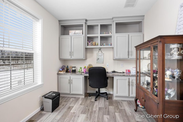 office with built in desk and light hardwood / wood-style flooring