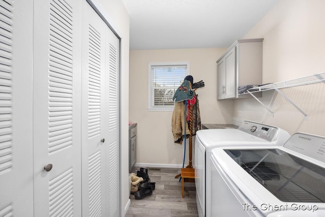 clothes washing area with washer and clothes dryer, cabinets, and light wood-type flooring