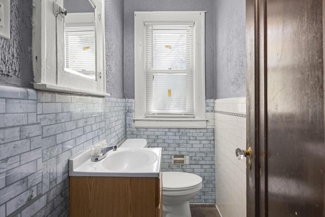 bathroom with vanity, toilet, and tile walls