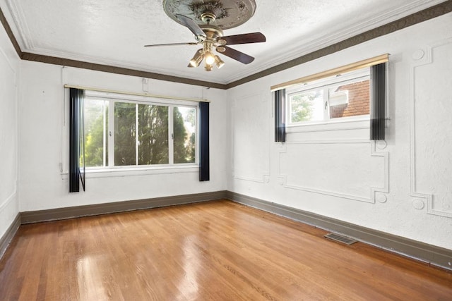 spare room with ornamental molding, a healthy amount of sunlight, hardwood / wood-style floors, and a textured ceiling