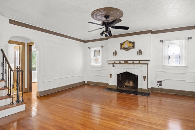 unfurnished living room featuring hardwood / wood-style flooring, ornamental molding, ceiling fan, and a textured ceiling