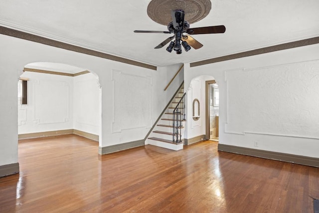 unfurnished living room with hardwood / wood-style flooring, ornamental molding, and ceiling fan