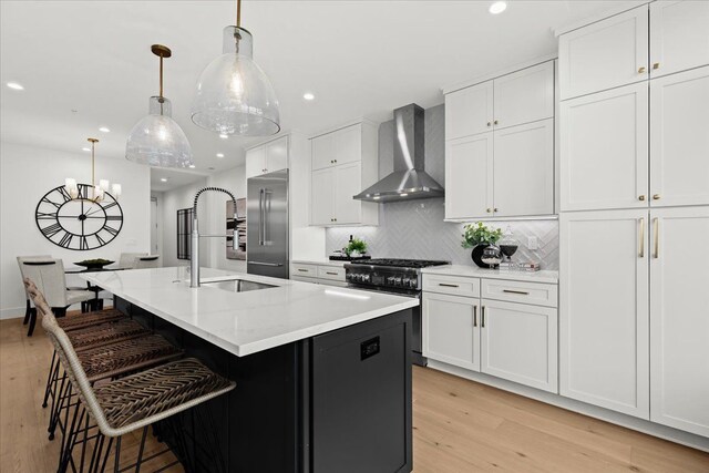 156 N Center St Unit 302, Northville, MI 48167 - kitchen featuring pendant lighting, high quality appliances, white cabinetry, a kitchen island with sink, and wall chimney exhaust hood