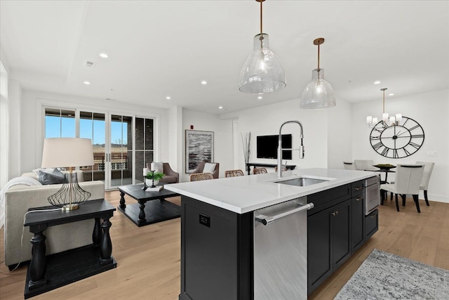 156 N Center St Unit 302, Northville, MI 48167 - kitchen featuring appliances with stainless steel finishes, decorative light fixtures, sink, a center island with sink, and light hardwood / wood-style flooring