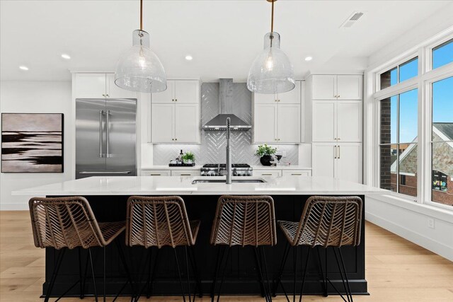 156 N Center St Unit 302, Northville, MI 48167 - kitchen with white cabinetry, wall chimney range hood, a center island with sink, and stainless steel built in refrigerator
