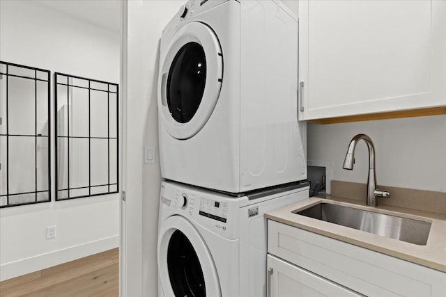 156 N Center St Unit 302, Northville, MI 48167 - laundry area featuring stacked washer / dryer, sink, cabinets, and light hardwood / wood-style flooring