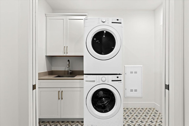 washroom featuring sink, cabinets, and stacked washer / dryer