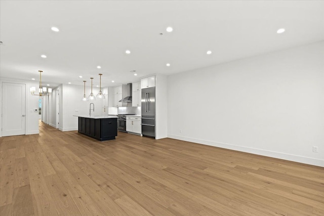 unfurnished living room featuring sink, light hardwood / wood-style floors, and a notable chandelier