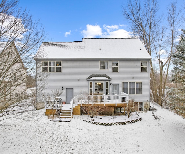 snow covered back of property with a deck