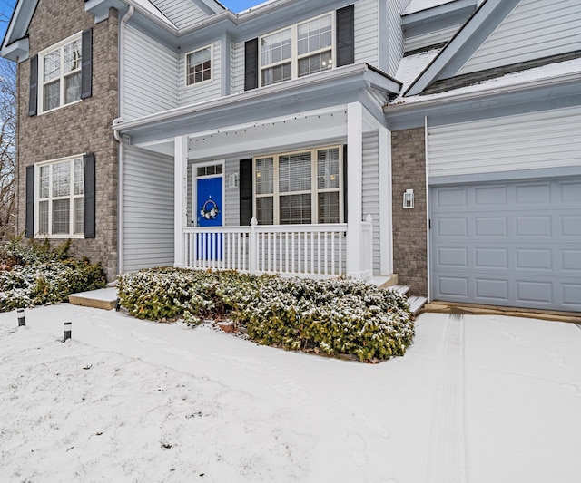 snow covered property entrance featuring a garage