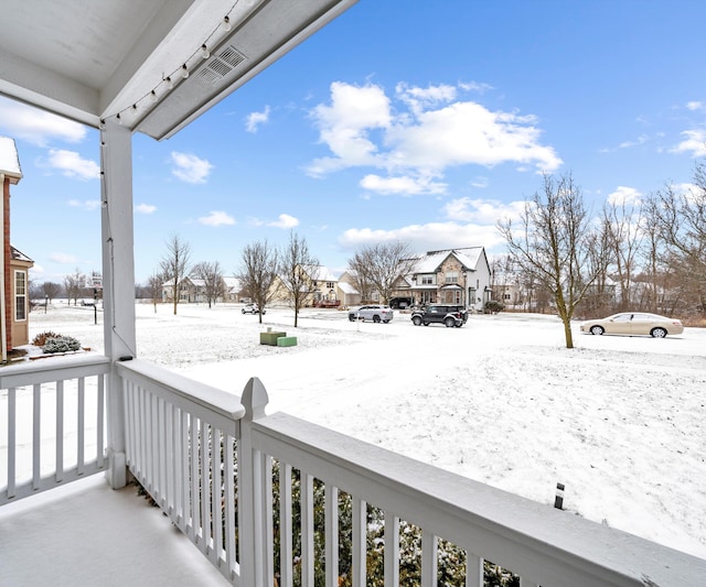 snow covered back of property with a porch