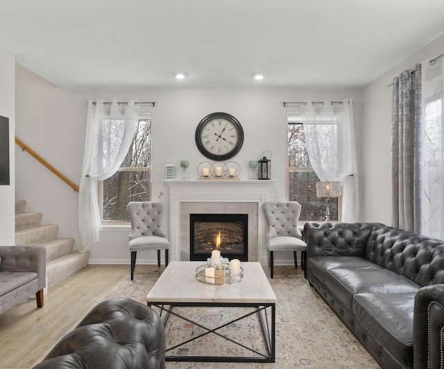 living room with a high end fireplace and wood-type flooring