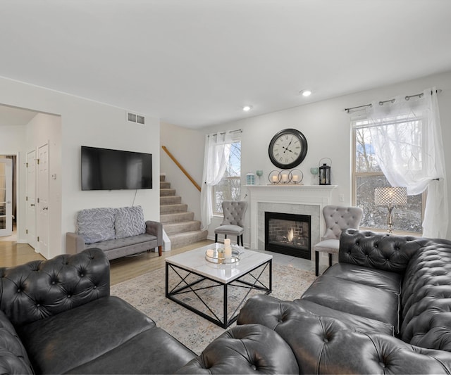 living room with a high end fireplace and light hardwood / wood-style floors