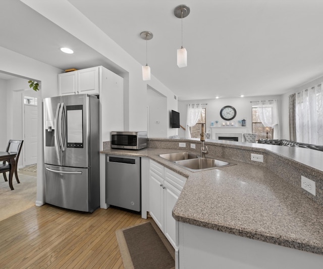 kitchen featuring white cabinetry, stainless steel appliances, sink, and hanging light fixtures