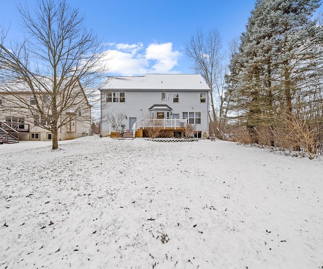 snow covered back of property featuring a wooden deck