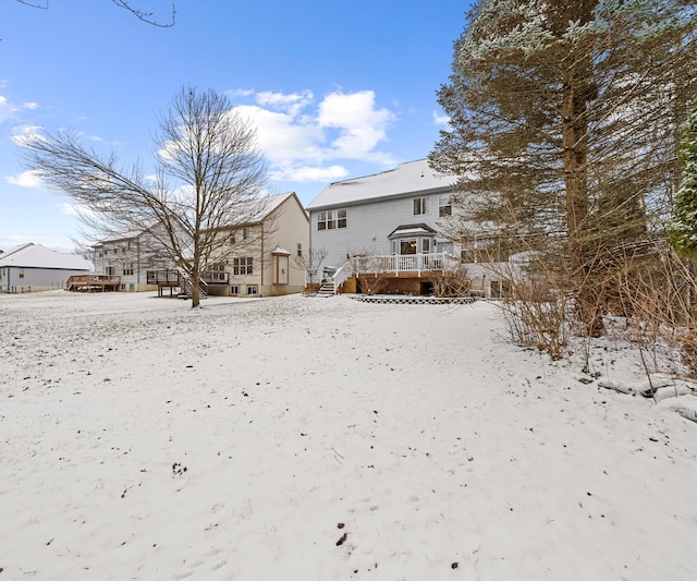 snow covered house featuring a wooden deck