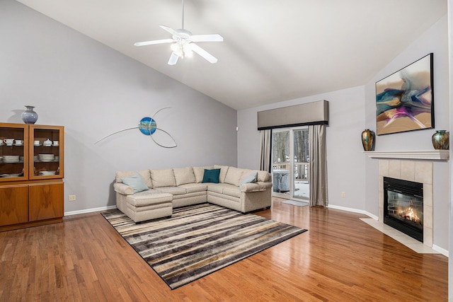 living room featuring hardwood / wood-style flooring, ceiling fan, high vaulted ceiling, and a tile fireplace