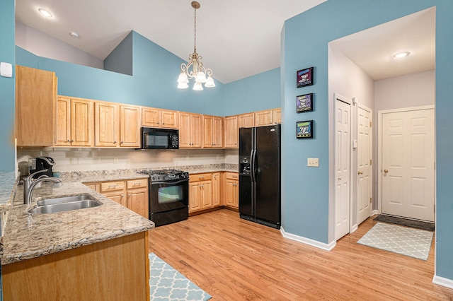 kitchen featuring sink, light brown cabinets, pendant lighting, light stone countertops, and black appliances