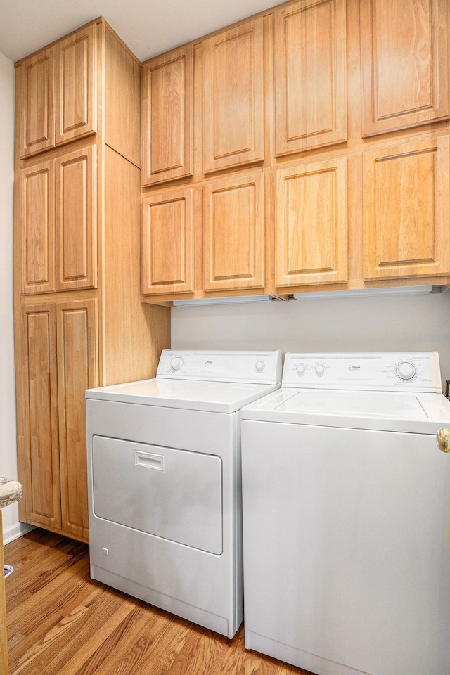 washroom with cabinets, washing machine and dryer, and light wood-type flooring