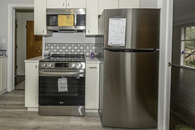 kitchen featuring tasteful backsplash, wood-type flooring, appliances with stainless steel finishes, and white cabinets