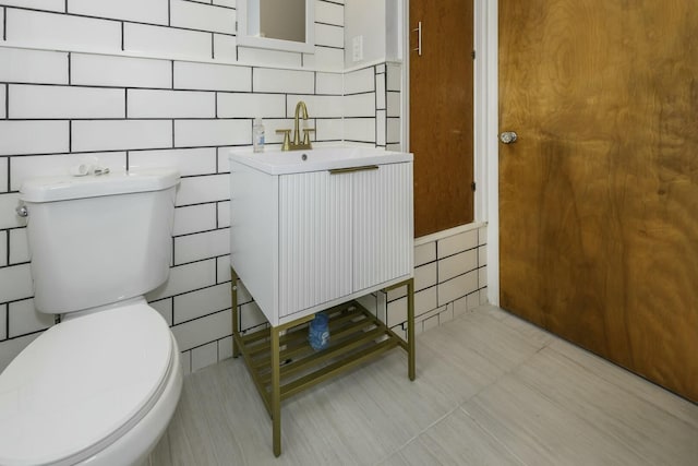 bathroom with vanity, tile walls, and toilet