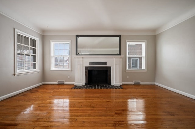 unfurnished living room with ornamental molding, wood-type flooring, and a tile fireplace