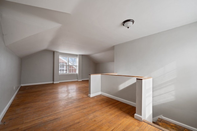 bonus room with hardwood / wood-style flooring and vaulted ceiling