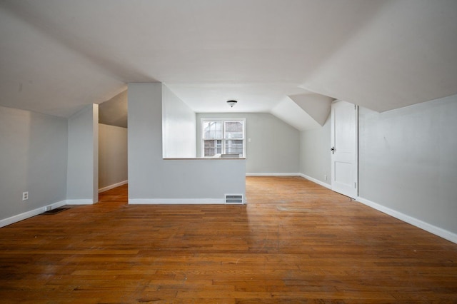 additional living space with lofted ceiling and hardwood / wood-style flooring