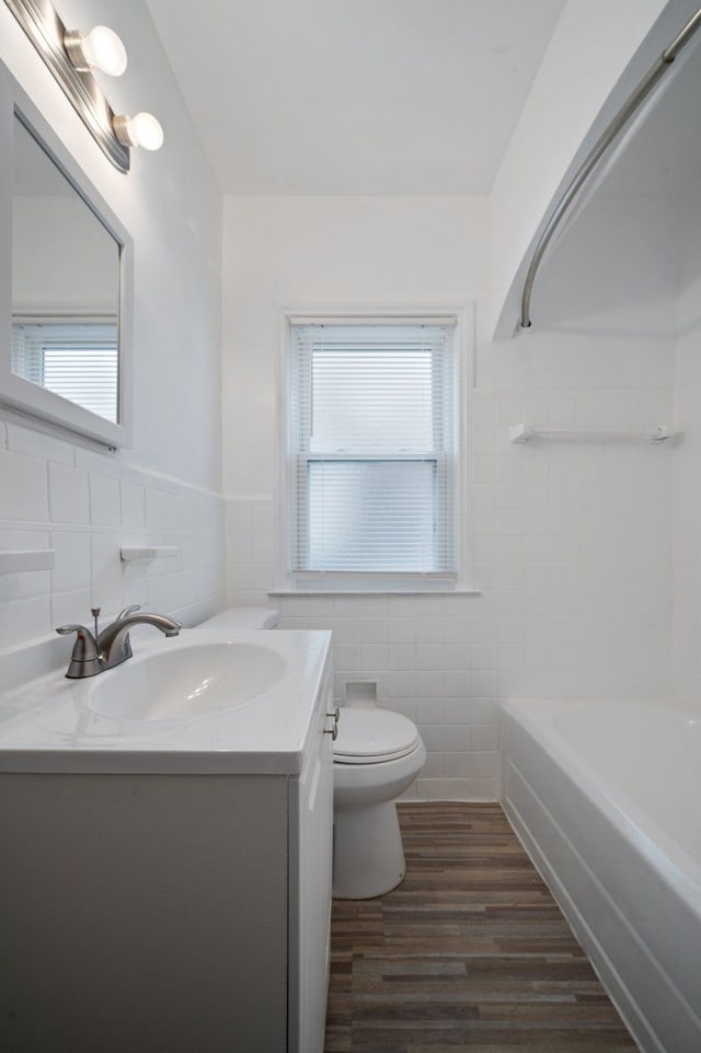 bathroom with hardwood / wood-style flooring, vanity, toilet, and tile walls