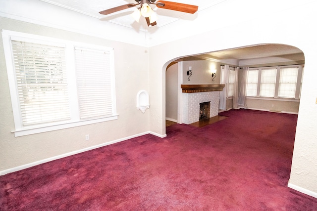 unfurnished living room with ceiling fan, a tray ceiling, carpet floors, and a brick fireplace