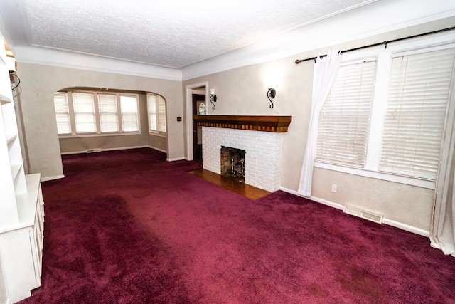 unfurnished living room with a brick fireplace, a textured ceiling, and dark colored carpet