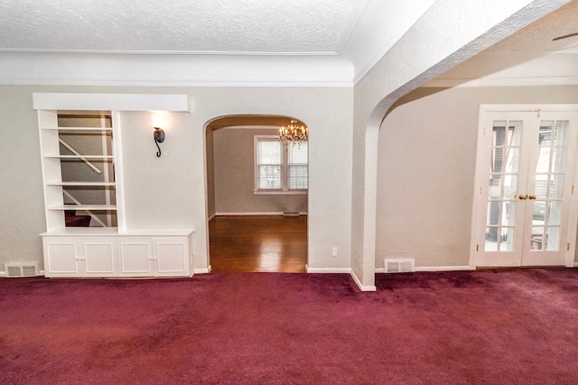 carpeted spare room with french doors and a textured ceiling