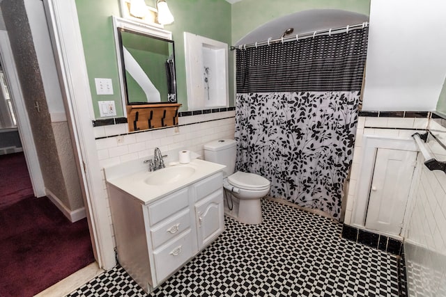 bathroom with tile walls, vanity, toilet, and walk in shower