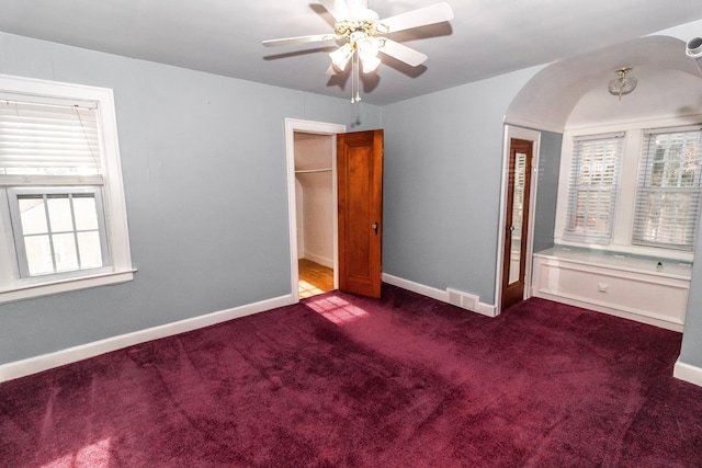 unfurnished bedroom with dark carpet and ceiling fan