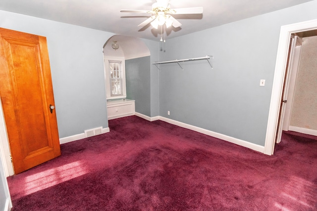 unfurnished bedroom with ceiling fan and dark colored carpet