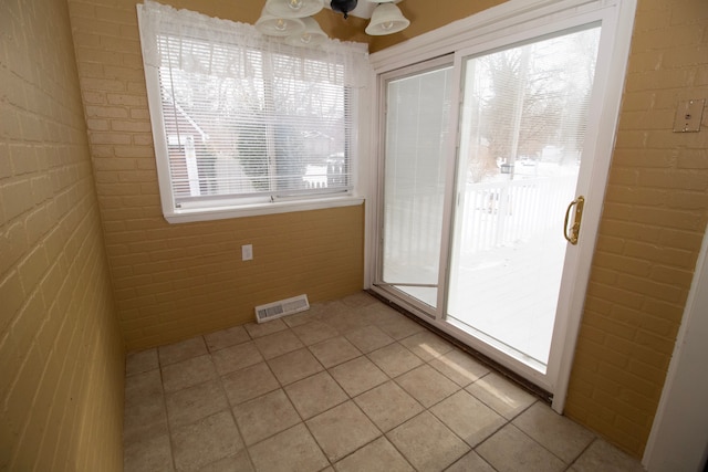 tiled spare room with brick wall